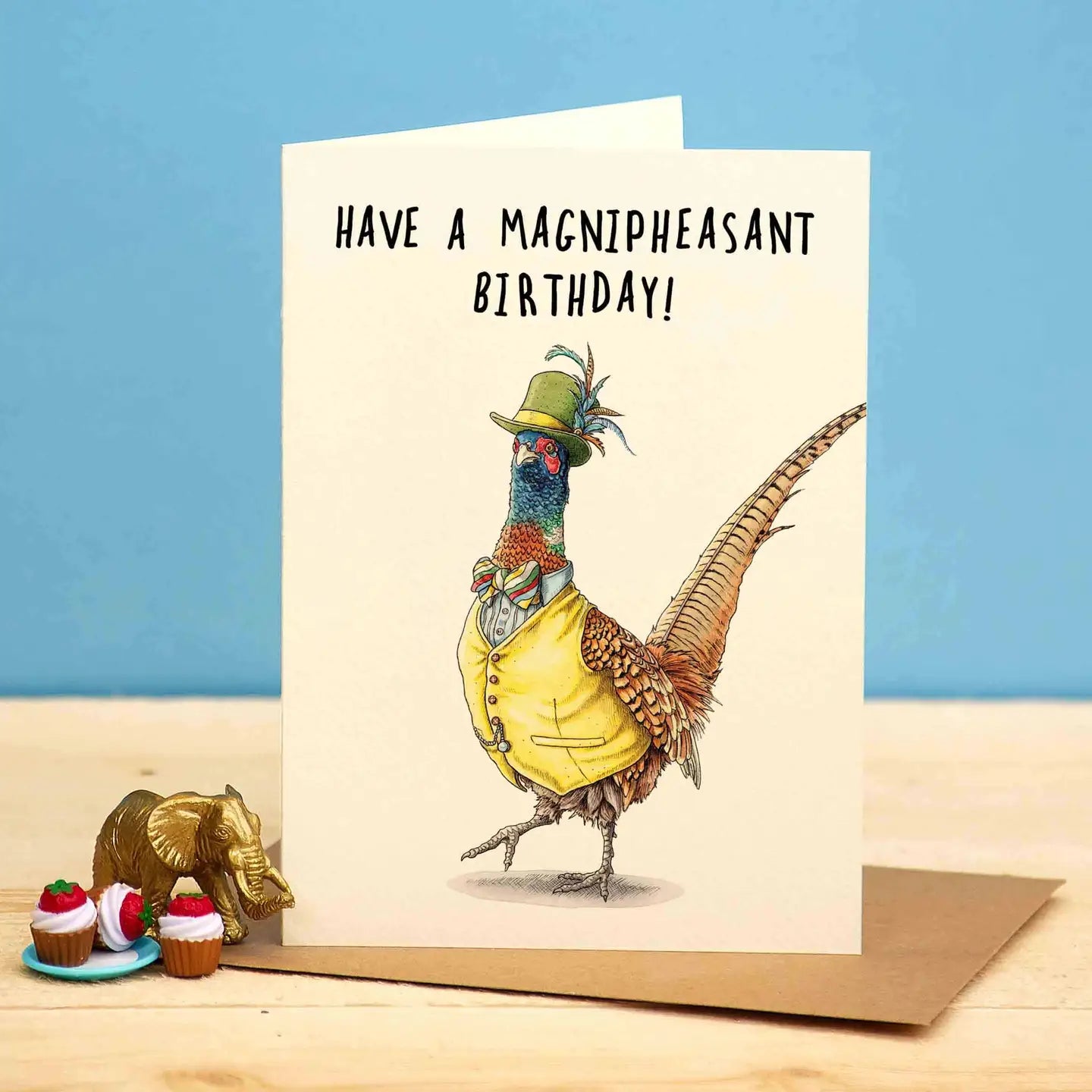 Birthday card featuring a chicly dressed pheasant wearing a feathered hat, shirt with bow tie and vest. Above it is the text "Have a Magnipheasant Birthday."